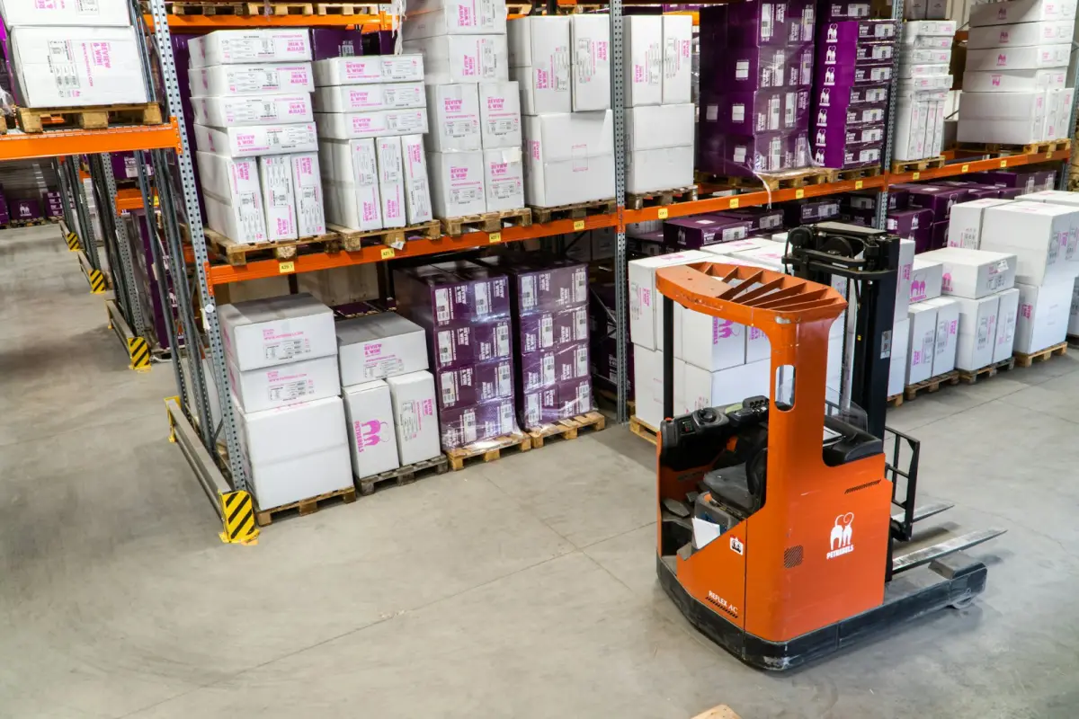 Cartons stacked on warehouse racking beside a forklift