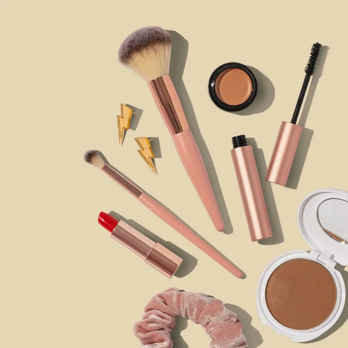 Makeup brushes, lipstick and compacts arranged on a neutral background